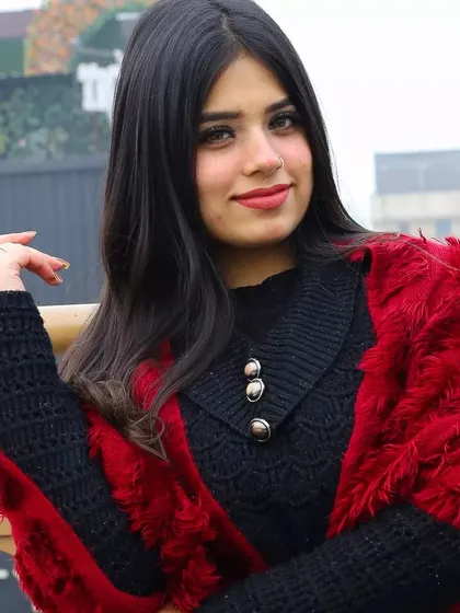 A close-up portrait from the winter series. This shot highlights the model's confident expression and the stylish details of her outfit, like the buttoned collar and cozy red wrap.