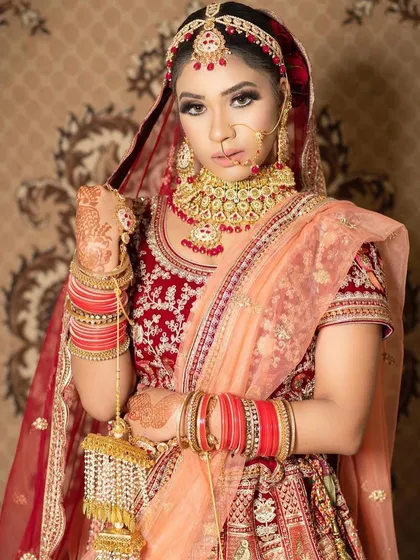 A confident pose from our client in her rented bridal attire. The peach dupatta softens the traditional red lehenga, creating a unique and modern look.