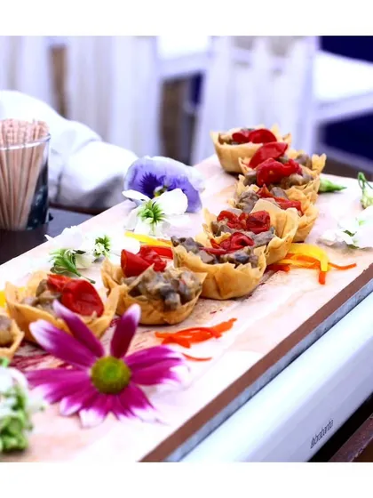 Miniature tart shells filled with a savoury mixture and garnished with edible flowers. These delicate bites showcase the artistry and precision of our pastry and garde manger team.