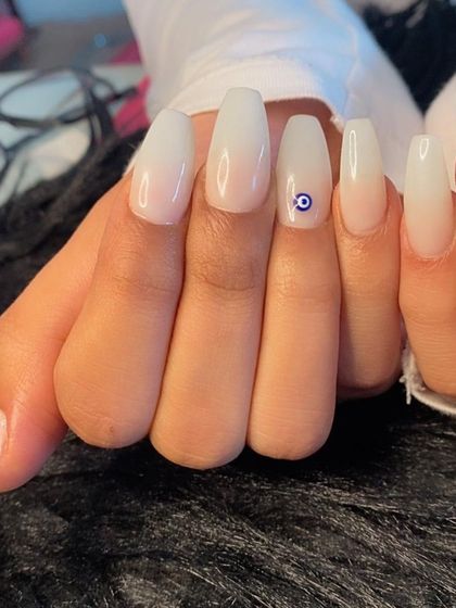 A close-up of the evil eye charm against the soft white ombré.