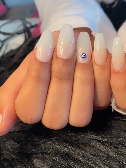 A close-up of the evil eye charm against the soft white ombré.