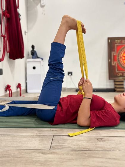 In Supta Padangusthasana I, we use two belts. One provides traction for the extended leg on the floor, while the other helps to gently guide the raised leg into a deeper hamstring stretch without compromising the alignment of the spine or pelvis.