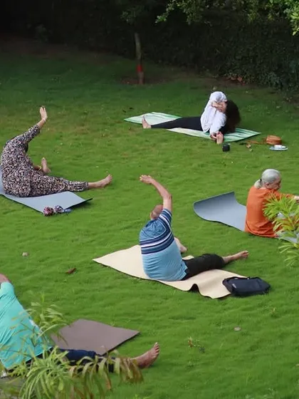 An outdoor yoga session in a beautiful green park. Practicing outside allows us to ground our energy and connect with the elements while we move and breathe.