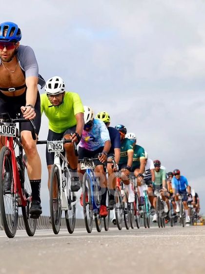 A long line of riders forms a peloton on the highway, a classic image of road racing that captures the scale of our events.