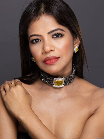 A bare-shouldered beauty shot, focusing entirely on the model's face and the statement choker.