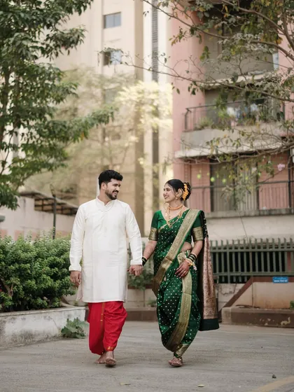 A candid shot of the couple walking hand-in-hand. The natural urban setting provides a lovely contrast to their traditional wedding clothes, telling a modern love story.
