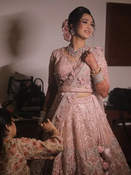 A beautiful shot of the bride getting ready, dressed in a stunning pastel pink floral lehenga.