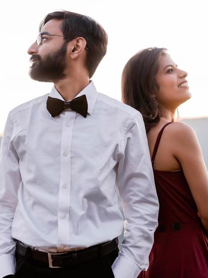 A classic back-to-back pose against a mountain backdrop at sunset. The warm light and their upward gazes create a hopeful and romantic image, symbolizing their shared future.
