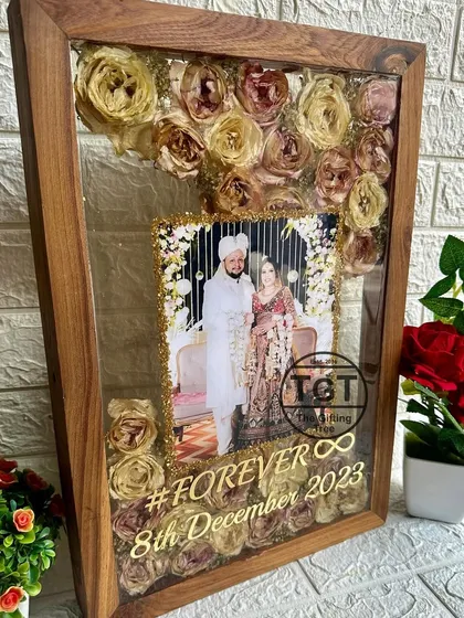 A large 13x19 inch teakwood frame preserving a wedding varmala. The design features a central photo with a glittery gold border and the hashtag #FOREVER.