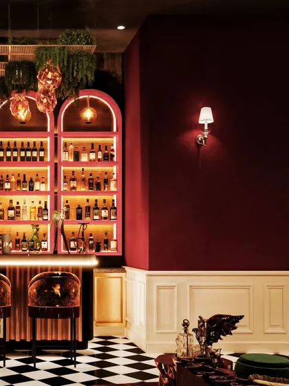 A close-up of a bar in Pune, with its pink-hued, backlit arched shelves and dramatic checkerboard floor.