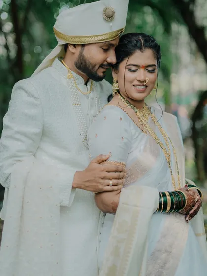 A tender and loving embrace between the couple in their beautiful white traditional attire. The groom's gentle hold and the bride's serene smile create a very romantic and peaceful mood.