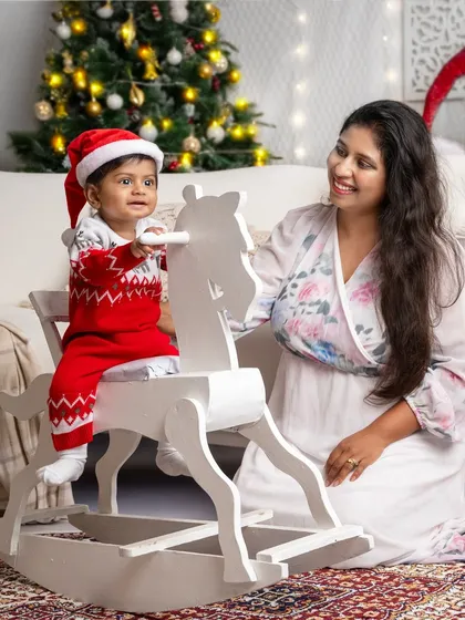 A mother helps her little one on the rocking horse, a sweet, interactive moment during their Christmas session.
