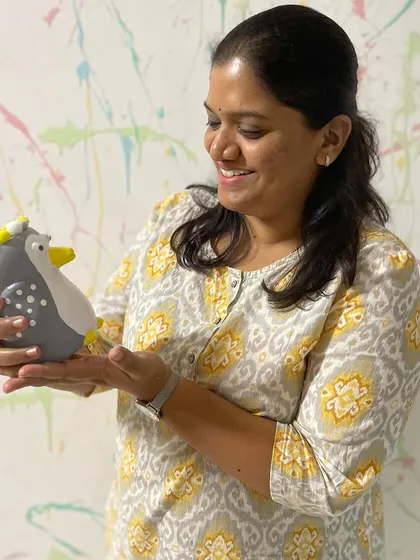 This participant is twinning with her art. She proudly holds the penguin planter she painted in matching yellow and grey.