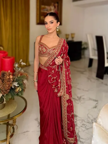 The full look, showcasing the elegant red saree and the sophisticated makeup. The clean bun and defined eyes create a look of timeless grace.