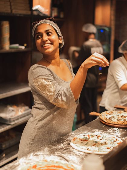 We call her the Parm Queen. One of our team members having a "salt bae" moment, sprinkling parmesan cheese with flair.