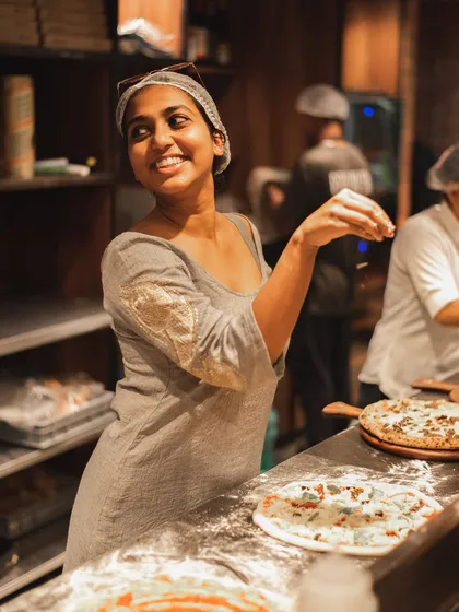 We call her the Parm Queen. One of our team members having a "salt bae" moment, sprinkling parmesan cheese with flair.
