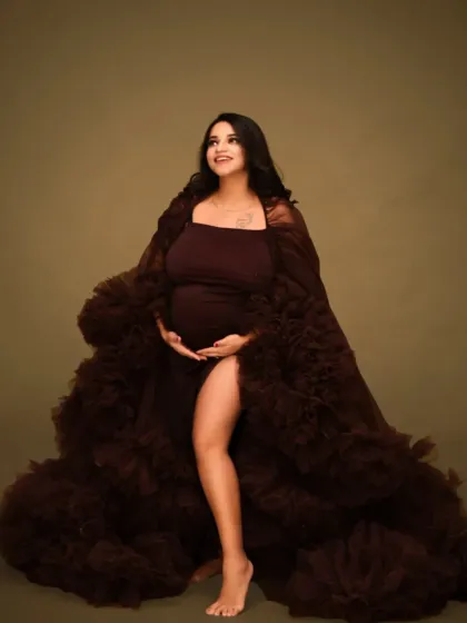 A full-length portrait showcasing a beautiful brown maternity gown. This classic pose highlights the baby bump and the elegance of the expecting mother.