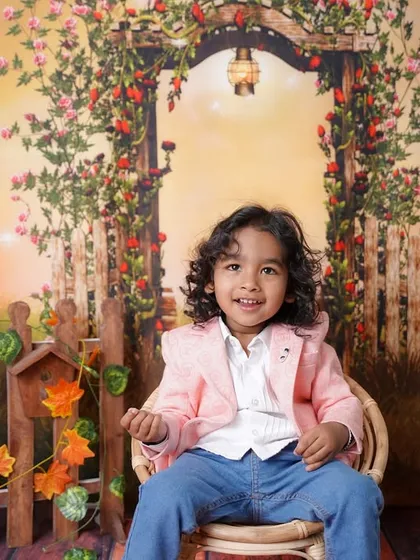 Relaxing in his wicker chair, this little boy looks perfectly at home in the magical, sunset-hued garden setting.