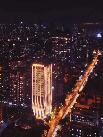 A wider cityscape view at night, with the ID Origins tower prominently featured, showcasing its impact on the local skyline.