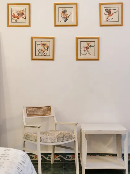 A detail of a seating area in a homestay, with a gallery wall of charming, vintage-style illustrations of cyclists. The decor is quirky, personal, and adds a touch of playful character.