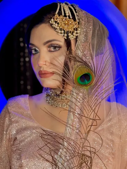A dramatic pose from a portfolio shoot, using a peacock feather to partially obscure the face for an artistic effect.