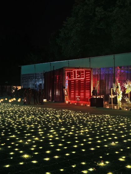 A magical outdoor setting with a field of lights creating a starry-night effect on the ground, leading to our glowing food stations.