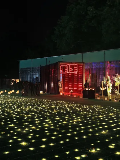 A magical outdoor setting with a field of lights creating a starry-night effect on the ground, leading to our glowing food stations.