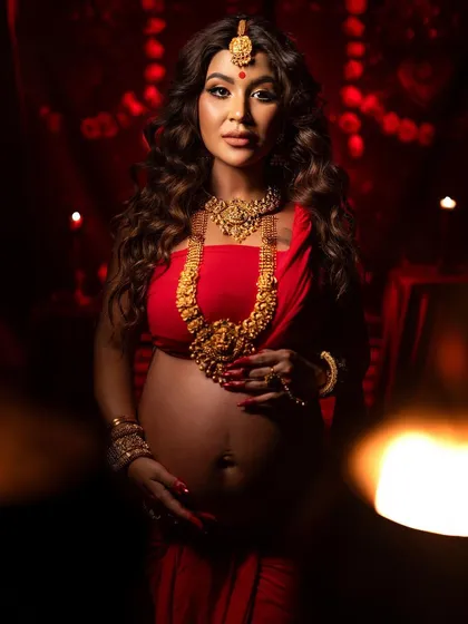A powerful and emotive portrait. The use of a foreground element adds a dreamy, artistic blur, drawing focus to the mother-to-be's strong presence and the traditional beauty of her attire.