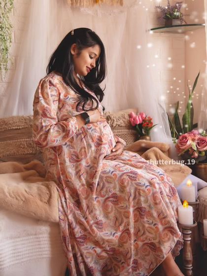 A beautiful solo shot of the mom-to-be cradling her bump in our cozy studio. The soft lighting and paisley-print dress contribute to the warm, bohemian feel of the portrait.