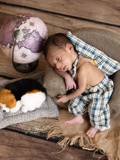 This little globetrotter is dreaming of his next adventure. The vintage props like the globe and the plaid outfit create a charming, story-filled portrait.