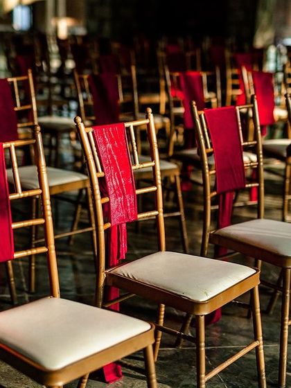 A shot of the wedding seating arrangement, with red sashes on the chairs, waiting for guests to arrive.