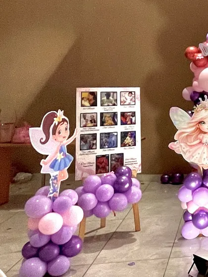 A personalized touch with a photo collage board displaying pictures of the birthday girl's first year, surrounded by fairy cutouts and balloons.