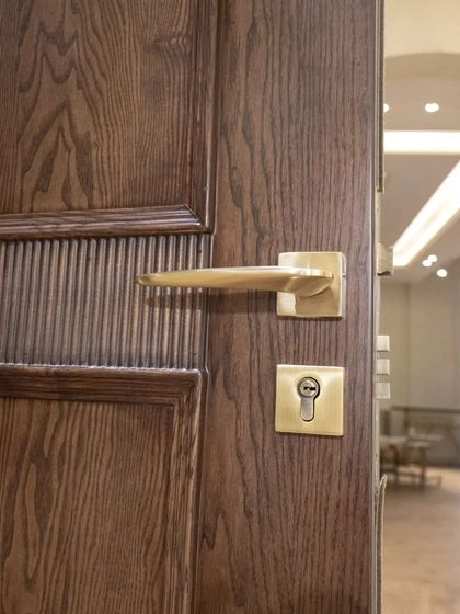 A close-up of the handle and lock on a real ash wood door, showing the beautiful grain and the CNC-carved fluted details.