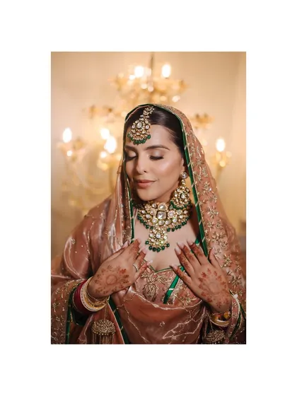 A beautiful, soft-focus portrait of a Sikh bride, her eyes closed, against a warmly lit background.