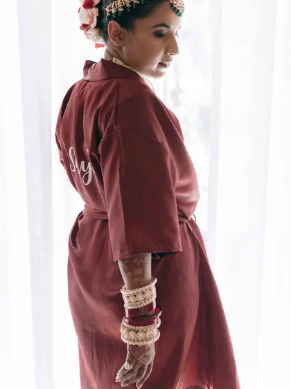 A getting-ready shot of the bride in her custom robe. This image captures a quiet, personal moment before the main events of the wedding day begin.