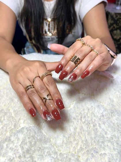 A beautiful set of square-shaped extensions in a deep red, with a sparkling silver glitter accent nail.