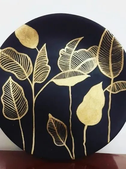 A modern take on botanical art, created with shimmering gold leaf on a dark circular canvas. I love how the simple, elegant leaf designs catch the light, making it a unique piece of home decor.