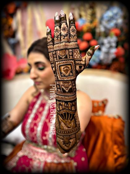 This bride is showcasing her full arm mehndi, which features detailed figures and architectural elements. This is a great example of a storytelling design that covers the entire arm in beautiful, intricate patterns.