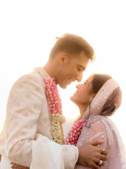 A sunlit portrait of a newly married couple, their faces close together. The natural light beautifully illuminates their features and the joy in their expressions.
