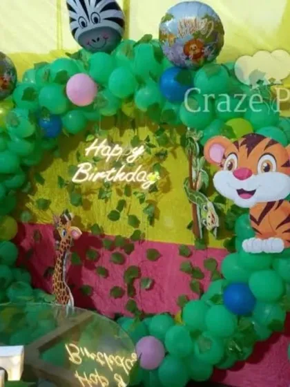 A vibrant jungle-themed ring backdrop for a kid's birthday. This setup uses a green balloon arch with leaf cutouts, fun animal characters, and a 'Happy Birthday' neon sign for a bright and cheerful look.