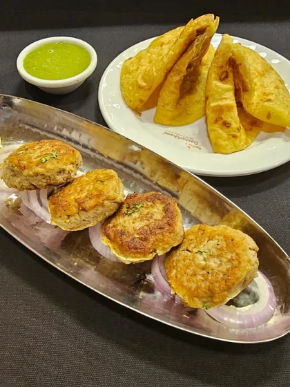 A plate of delicate Galouti Kebabs served with a side of green chutney and parathas. This dish is a testament to the rich culinary heritage of the Nawabs.