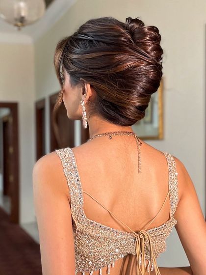The back view of a sophisticated, voluminous updo. I created this style with interwoven sections to give it a modern texture while maintaining a classic bun shape.