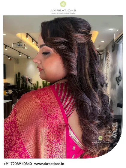 An elegant half-up hairstyle with voluminous curls, perfect for showcasing both the hair's length and a beautiful saree back.