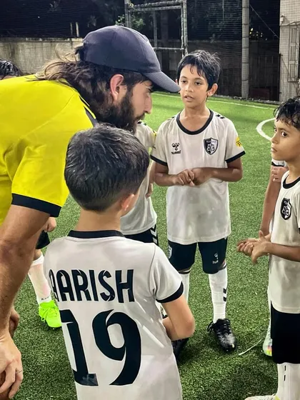 A coach engages with our young players during a team talk. We believe in asking questions and mentoring to develop not just skilled athletes, but thoughtful individuals.