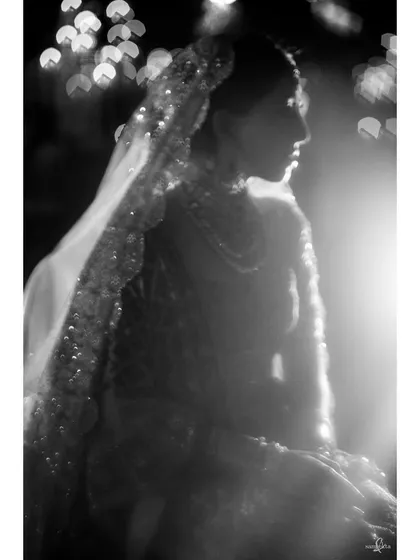 An ethereal, soft-focus portrait of the bride, Shachi. The dreamy bokeh and gentle light in this black and white photo give it a timeless and romantic quality.