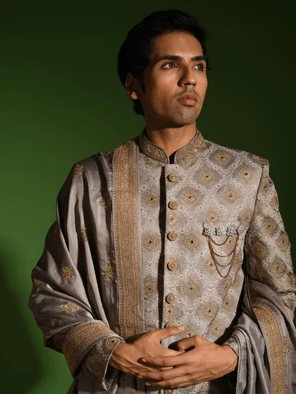 This angle highlights the structure and fit of the steel grey sherwani. Notice the hand embroidered zardozi buttons and the subtle chain brooch, which are signature details I add to elevate the garment.