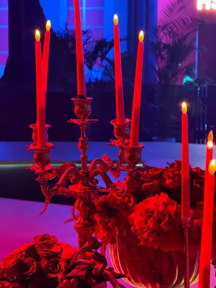 Atmosphere is created with light and texture. This image captures the moody, luxurious feel of the Ajio Luxe gala, with ornate candelabras and red taper candles casting a warm glow over the rich, floral-adorned tables.