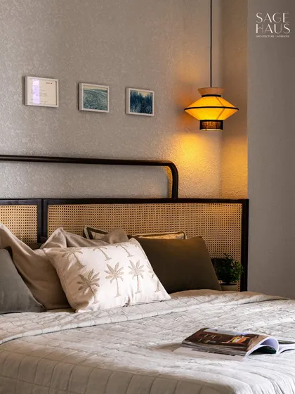 A closer look at the layered textures in this bedroom. The palm-print cushion adds a subtle tropical touch, while the open book invites you to unwind.