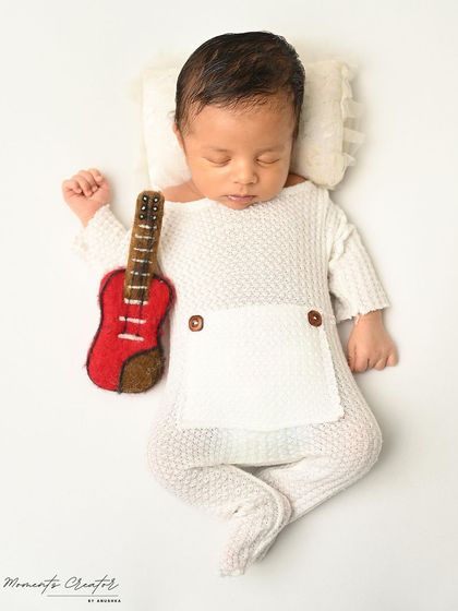 A tiny musician and his guitar. This minimalist setup on a clean white background puts all the focus on the adorable, sleeping baby.