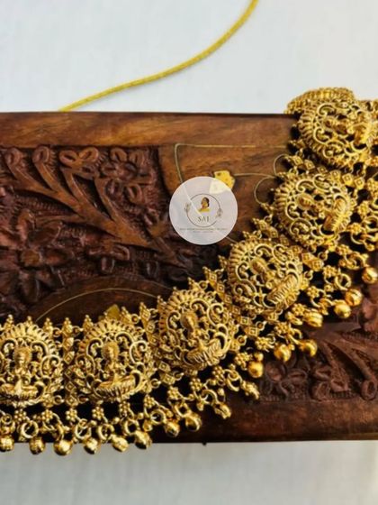 A close-up of a classic temple jewellery choker. The design features Goddess Lakshmi motifs across the necklace, finished with delicate golden beads for a timeless look.